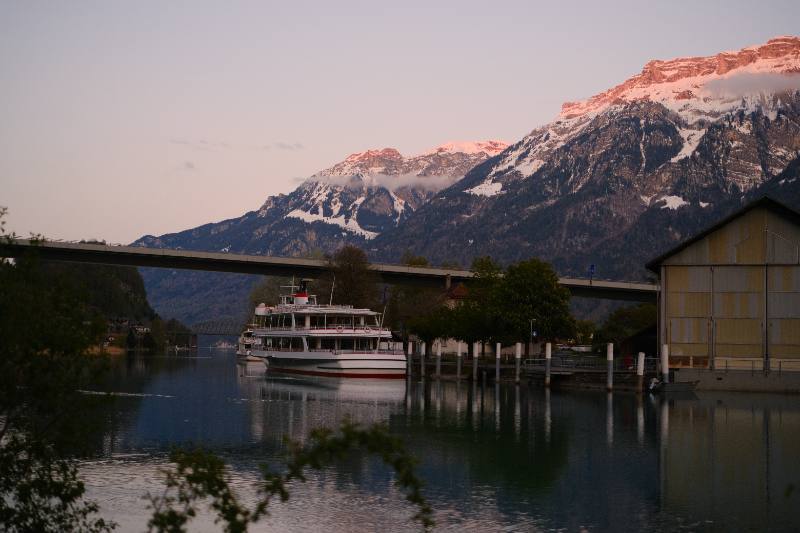 Passenger boat on a mountain lake beneath a pink evening sky